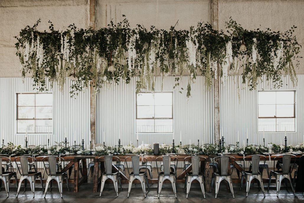 wedding reception tables with hanging greenery and lights at The Gin at Hidalgo Farms