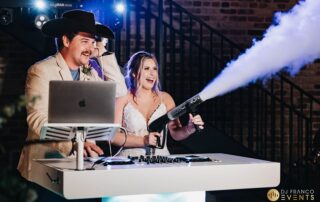 A Texas wedding couple behind the DJ console with the bride manning a CO2 gun.